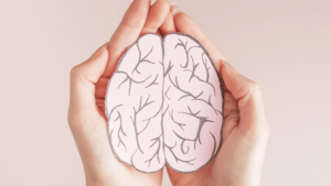 A flat cardboard cutout of a human brain cupped by two hands, meant to symbolize mental health.