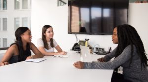 Two women interviewing another woman at a table